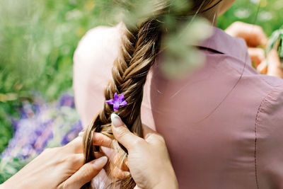 Girl braids a flower in a braid on nature