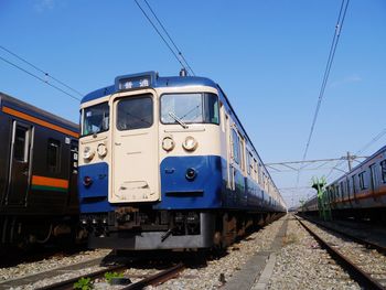 Train on railroad tracks against clear blue sky