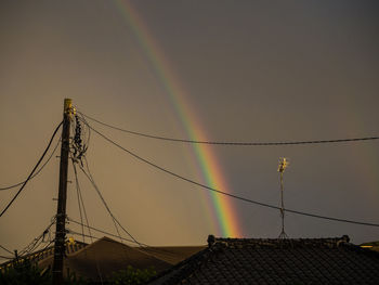 Low angle view of rainbow over building against sky