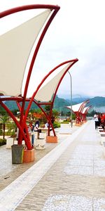 Bridge over footpath in city against sky