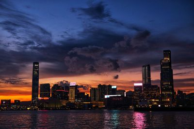 Illuminated buildings in city against sky during sunset