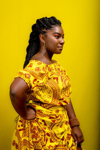 Young beautiful woman standing wearing colorful outfit. isolated against yellow background.