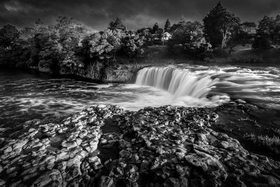 View of waterfall against cloudy sky