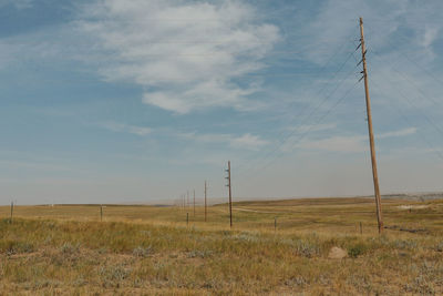 Scenic view of field against sky, electric power lines