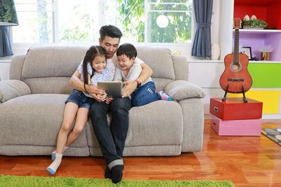 
father and kids sitting on sofa at home
