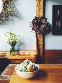 Food served in bowl on wooden table against wall with decoration