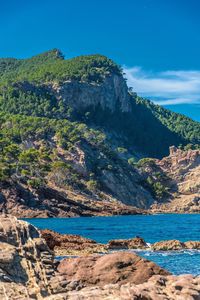 Scenic view of sea and mountains against blue sky