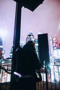 Rear view of woman standing in city at night
