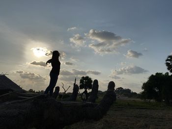 Silhouette man standing on field against sky during sunset