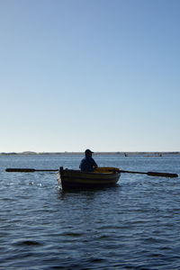 Man in boat on sea against clear sky
