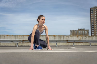 Woman working out outdoors. lady doing exercises and ready to start running. 