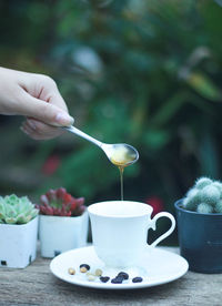 Cropped image of hand pouring coffee cup on table