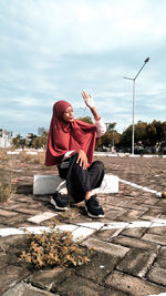 Teenage girl wearing hijab shielding eyes while sitting outdoors