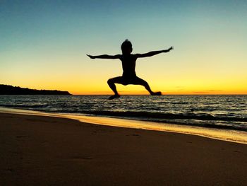 Silhouette man jumping on beach against sky during sunset