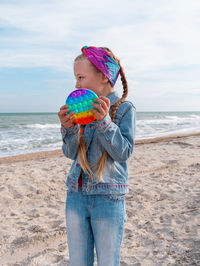 Happy child rainbow pop it toy beach girl walking on sea background antistress sensory simple dimple