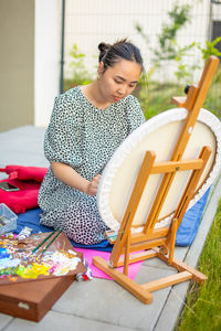 Woman painting while sitting outdoors