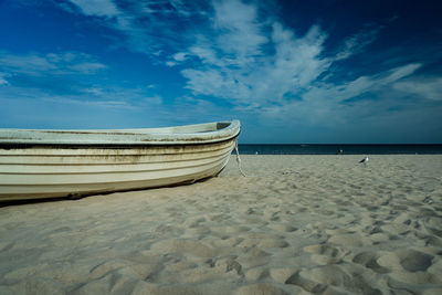 Boat moored on beach against sky