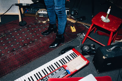 Low section of female musician standing by instruments on floor at studio