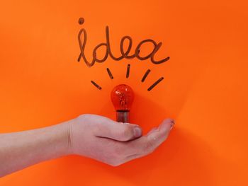 Close-up of woman hand against orange wall