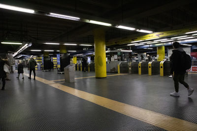 Rear view of people walking on railroad station platform