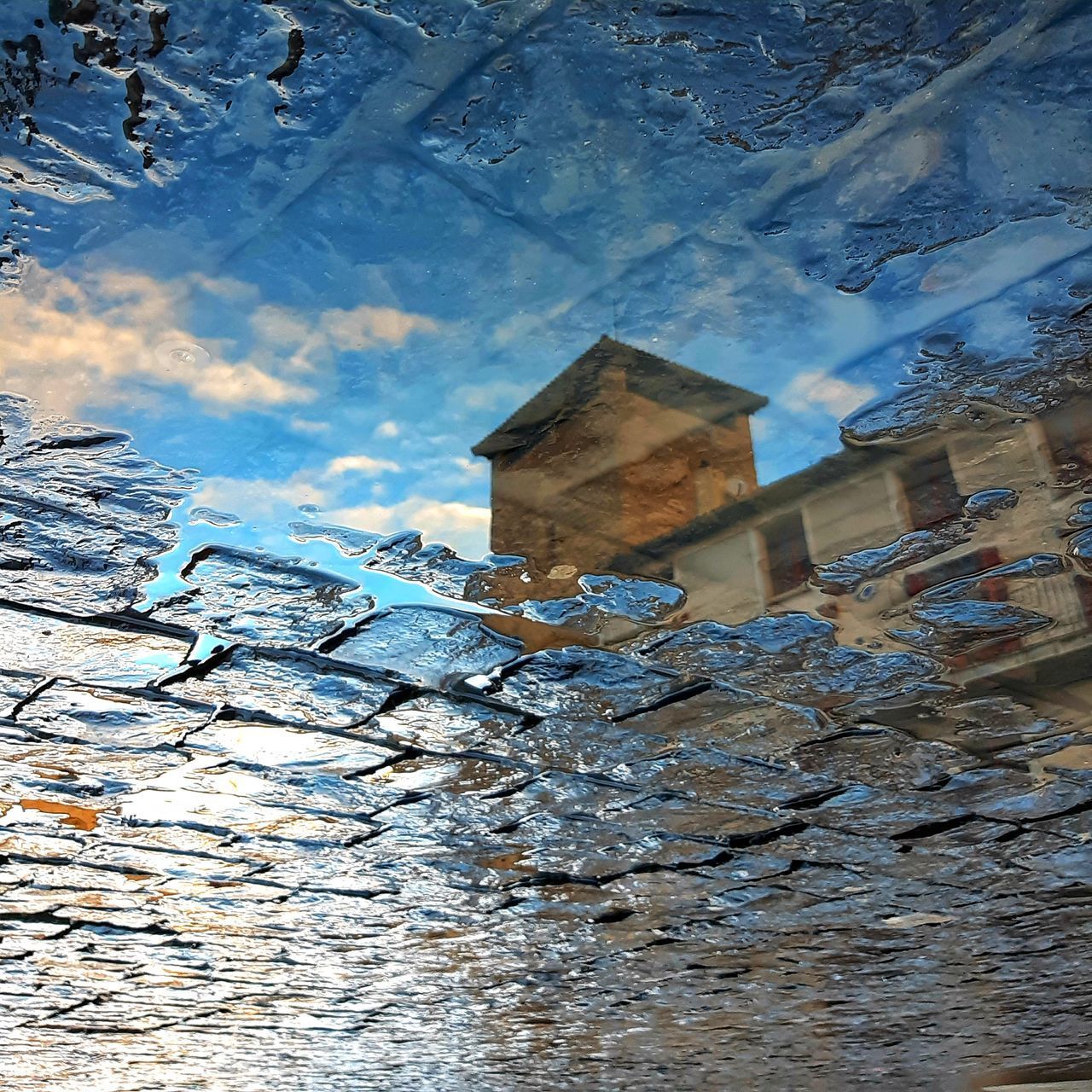LOW ANGLE VIEW OF BUILDING AGAINST SKY IN PUDDLE