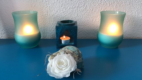 Close-up of lit candles on table against wall