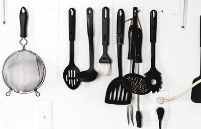 Kitchen utensils hanging on white wall