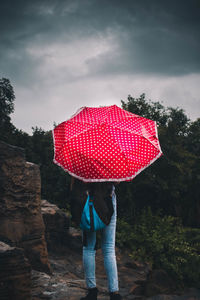 Rear view of woman with umbrella standing in rain