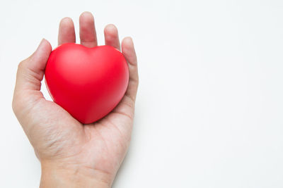 Close-up of hand holding heart shape over white background