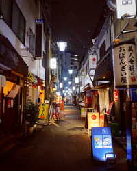 Illuminated street amidst buildings in city at night