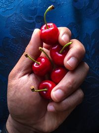 Cropped hand of man holding cherries