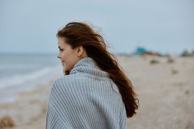 Side view of young woman standing at beach
