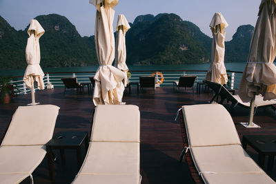 Lounge chair with closed parasol on boat against mountain