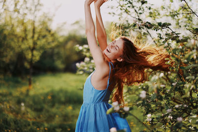 Portrait of young woman standing against trees