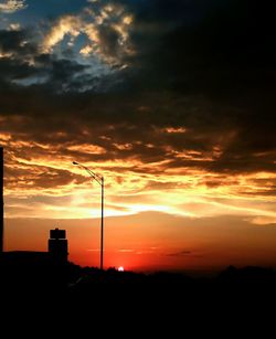 Silhouette electricity pylon against sky during sunset