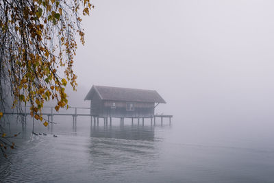 House by lake and building against clear sky