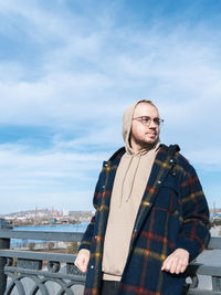 Portrait of young man standing against sky