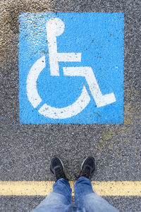 A man standing in front of the symbol on the cobblestones in the area for disabled people