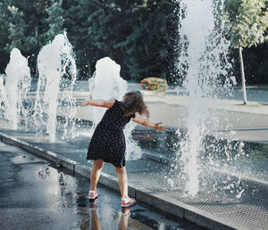 Full length of girl playing in water fountain at town square