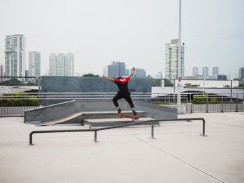 Full length of man skateboarding on city against sky