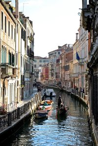 Boats in canal amidst buildings against clear sky