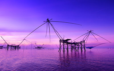 Fishing net on sea against sky during sunset