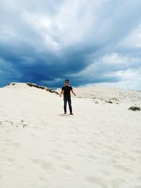 Full length of man standing on sand at beach against sky