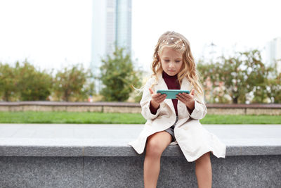 Full length portrait of woman sitting on mobile phone