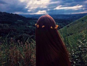 Rear view of woman wearing flowers against mountains