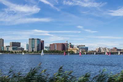 City buildings by river against sky