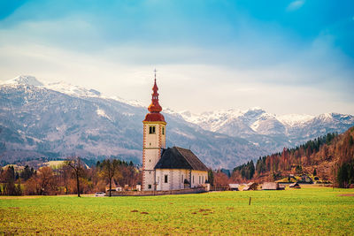 Scenic view of field by buildings against sky