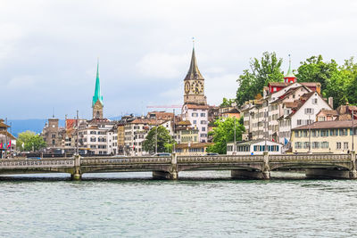 Bridge over river against buildings in city