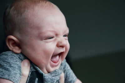 Cropped hands of mother carrying son at home