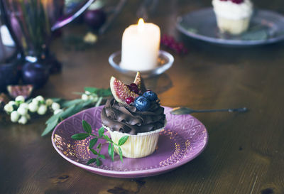 Tea light candles and cupcake in plate on table